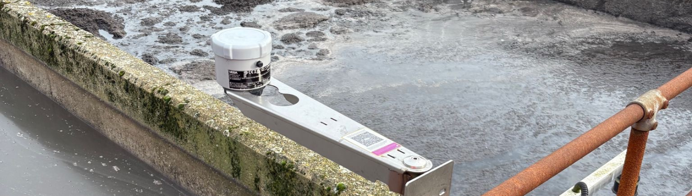 Ein Radar-Füllstandssensor der Serie VEGAPULS Air auf einer Halterung über dem Schlammrückhaltebecken.