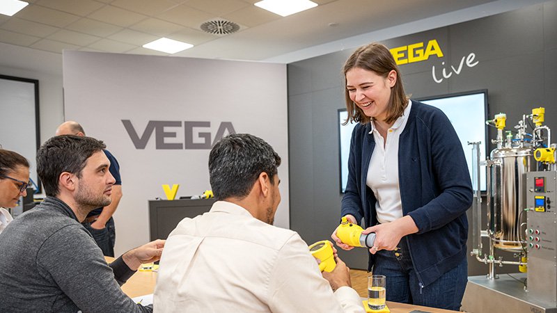 Vega Mitarbeiterin zeigt Schulungsteilnehmer einen Vega Sensor